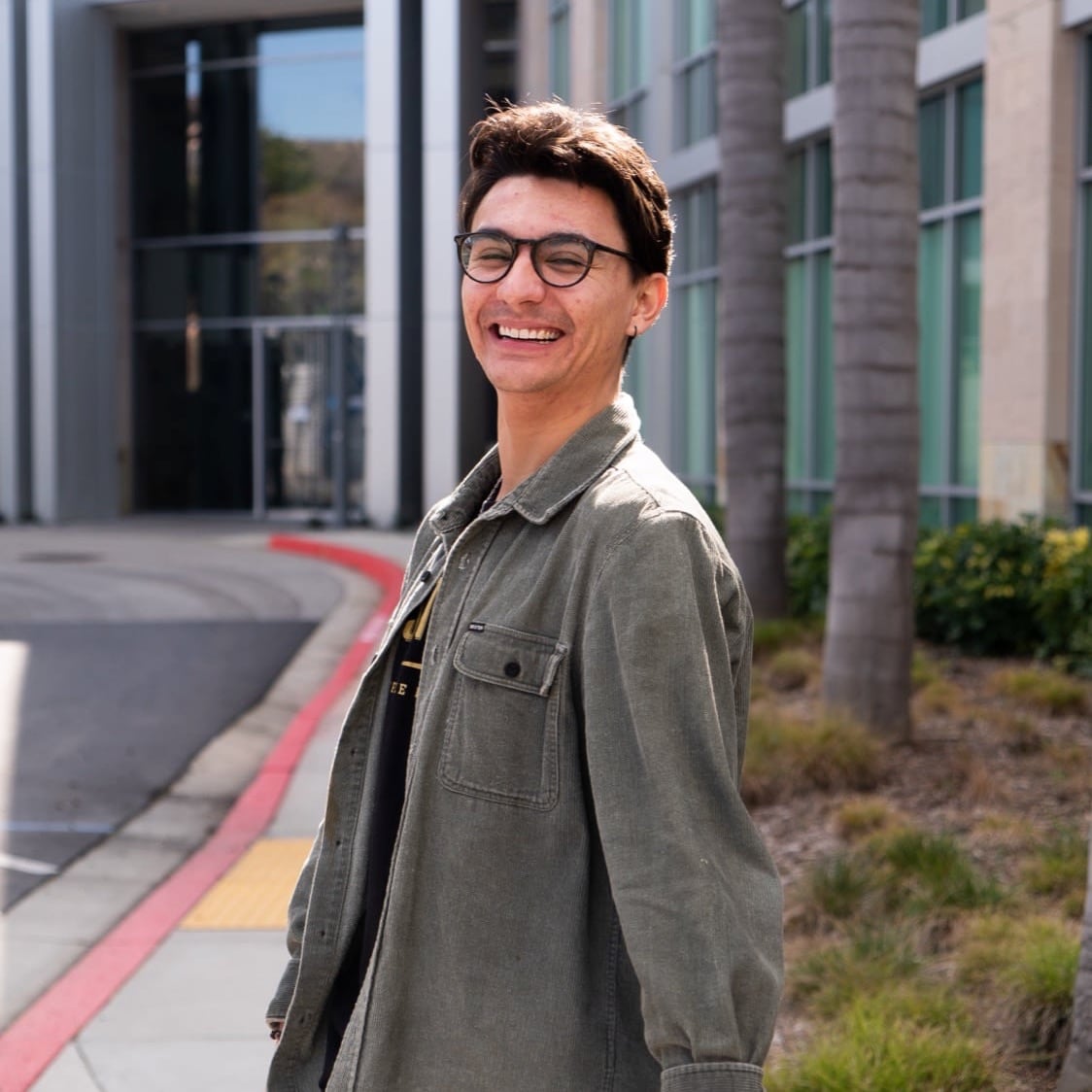 Ryan smiling in front of a building wearing glasses